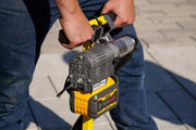 Person holding a yellow and black power tool with branding on a blurred background.