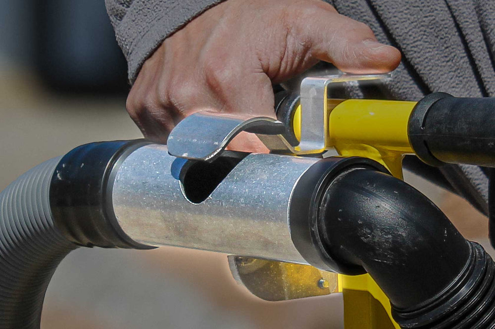 Close-up of a hand holding a yellow and black hose connector.